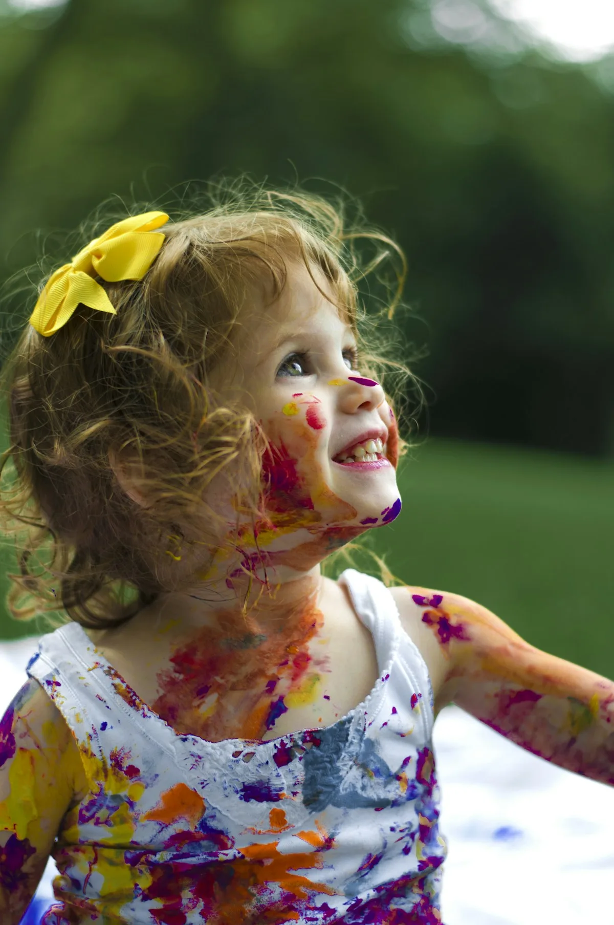 Criança brincando com tintas coloridas, em imagem ilustrativa sobre a infância
